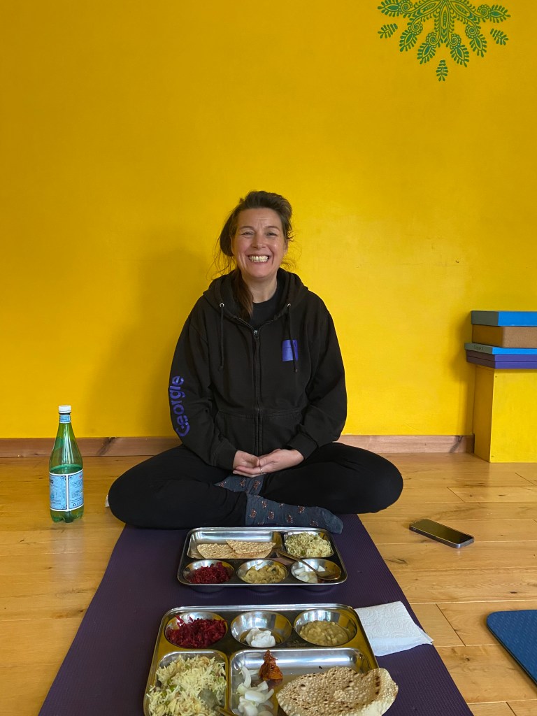 Yoga student enjoying a South Indian Thali meal after class, prepared with fresh vegetables from Smitha’s allotment in Welwyn Garden City.