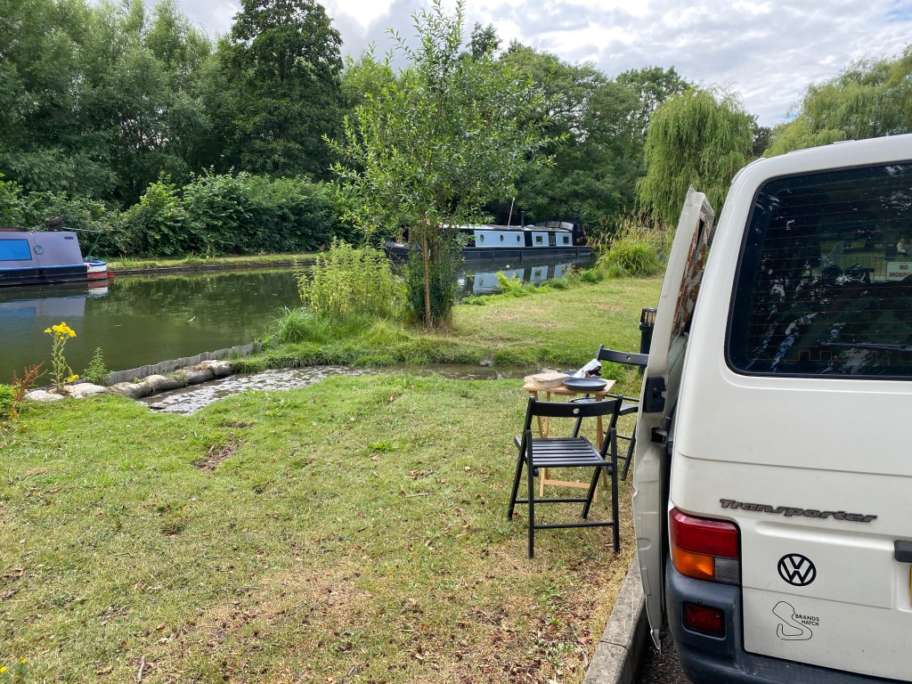 My VW camper van parked beside the Berkhamsted canal, with a little table set for lunch and narrowboats moored quietly on the opposite bank.