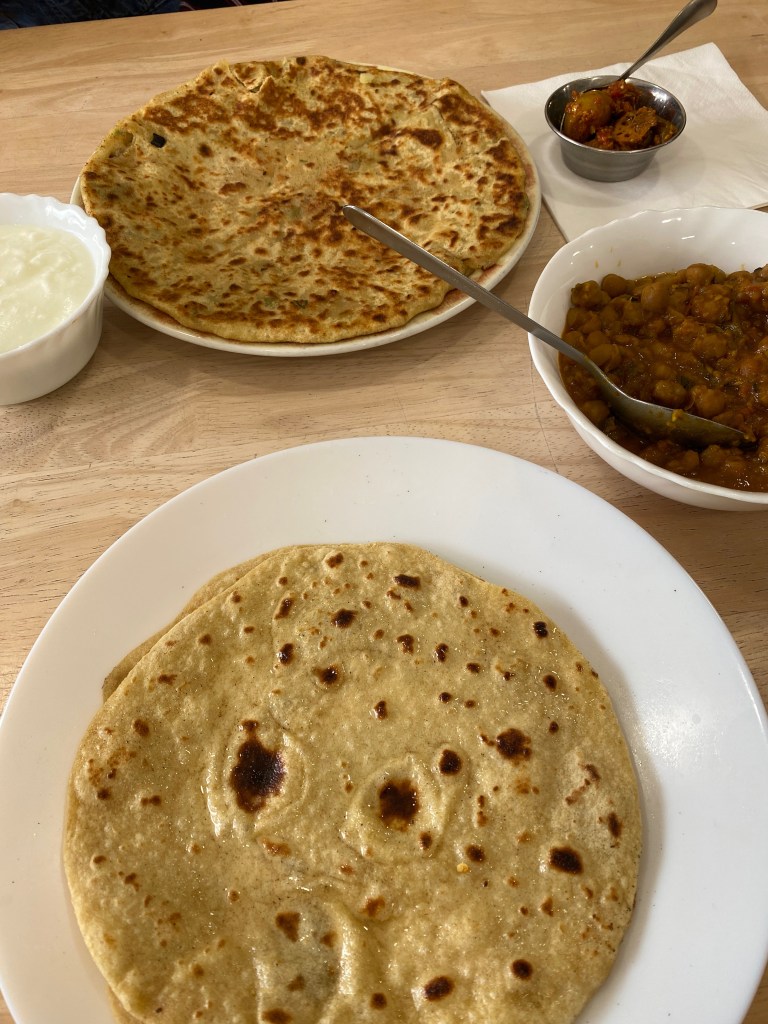 Aloo paratha with mango pickle, chickpea curry and corn chapatis served as a traditional Indian meal